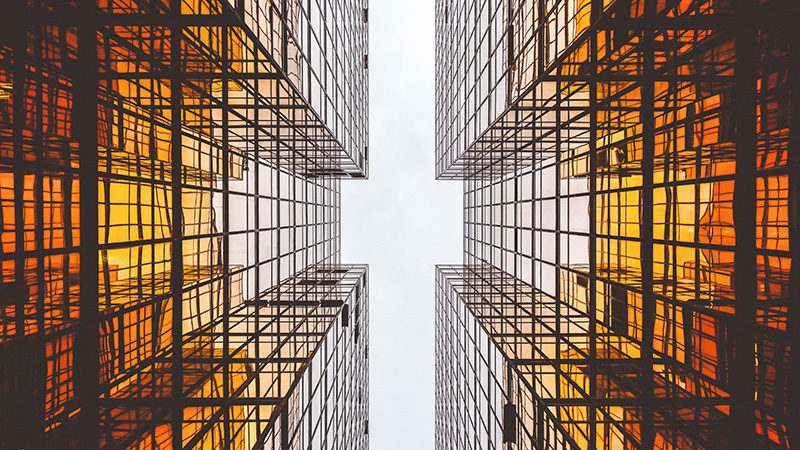 Towering glass buildings, seen upwards from the ground.