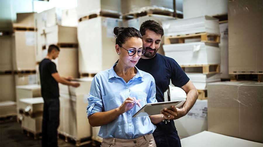 Business workers looking at a tablet, in a warehouse.