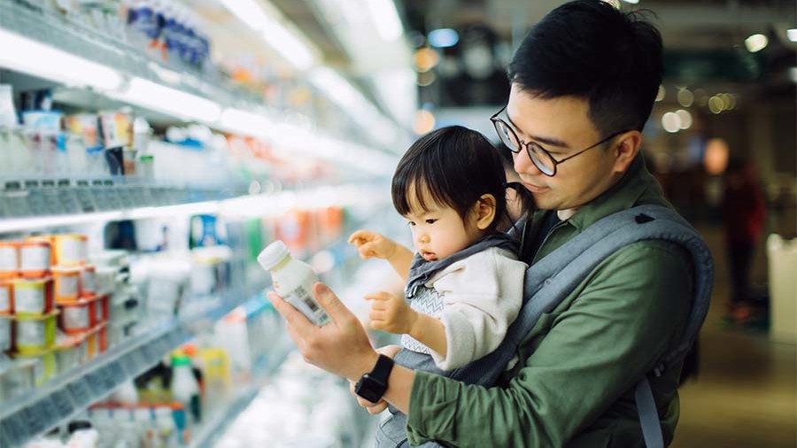 Man with a baby in a front facing carrier, at a grocery store.