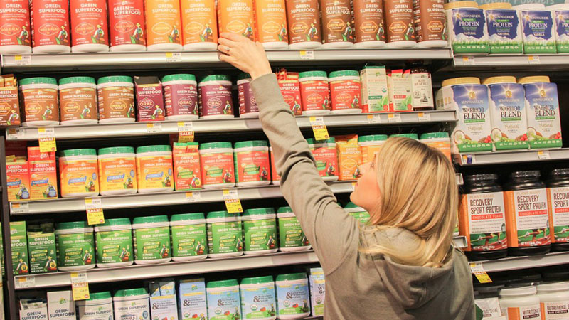 Woman selecting a health food product from a store shelf.