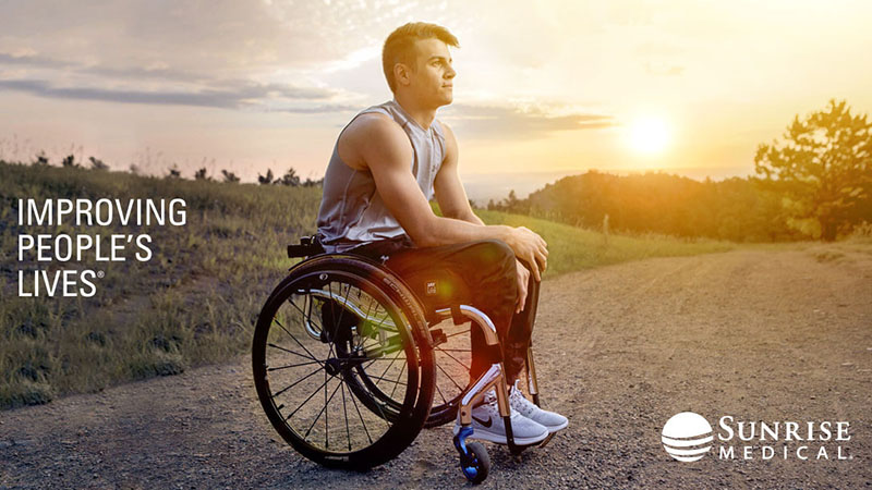 Man in a wheelchair, outside at sunset.