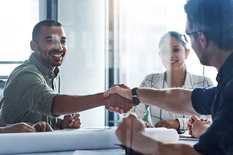 Business people shaking hands over a conference table.