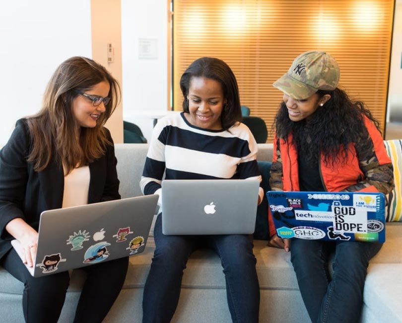 Three diverse young women with laptops